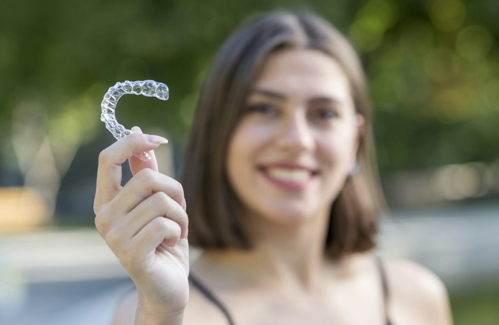 Beautiful smiling Turkish woman is holding an invisalign bracer