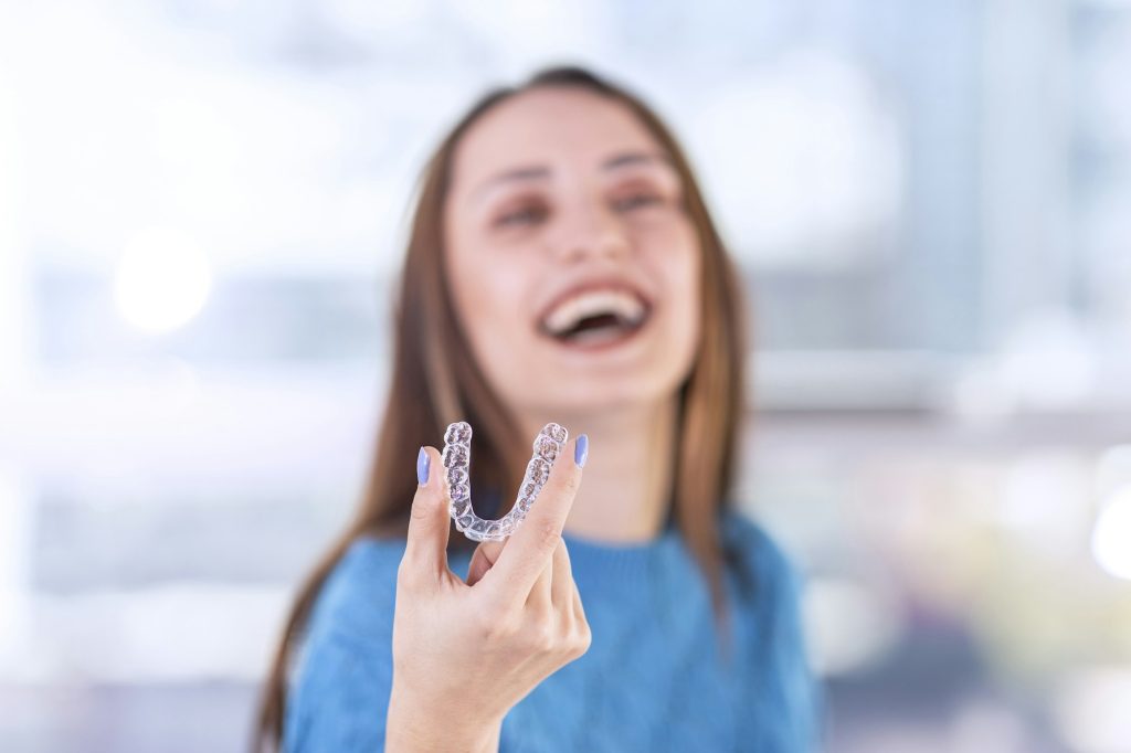 Beautiful smiling Turkish woman is holding an invisalign bracer, includes copy space